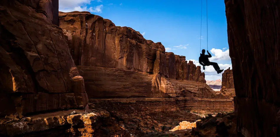 a man single-strand rappelling in a canyon