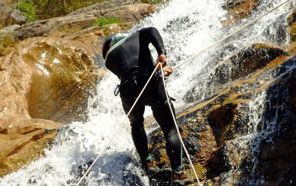 A man rappels down a waterfall with two ropes in his hand